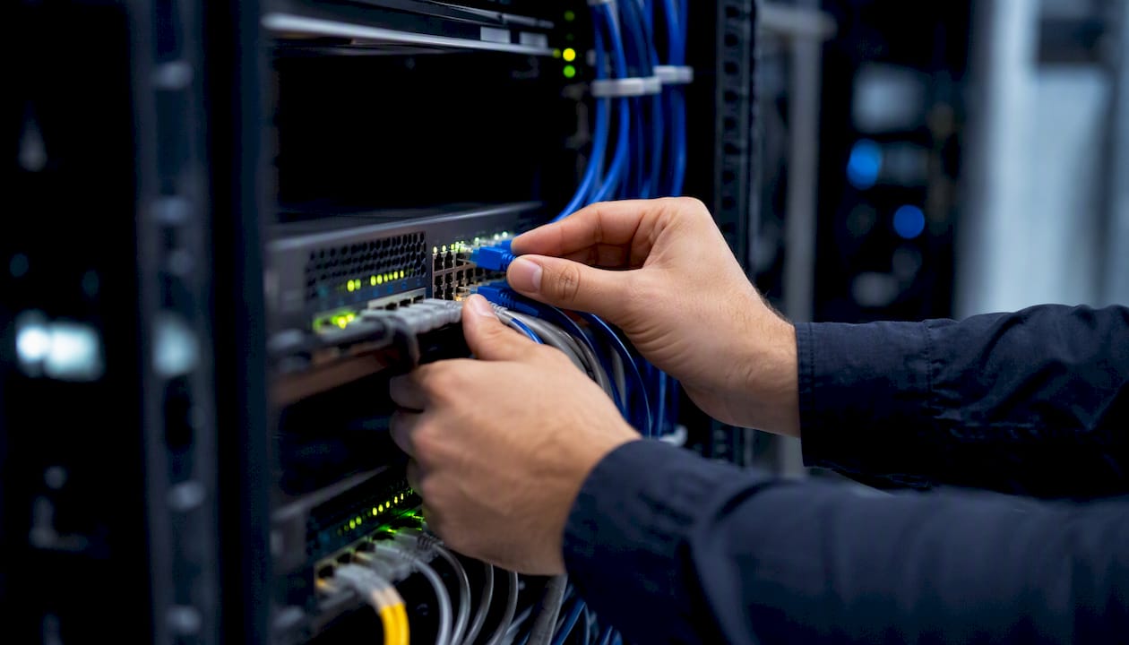 Hands wiring patch cables in server rack